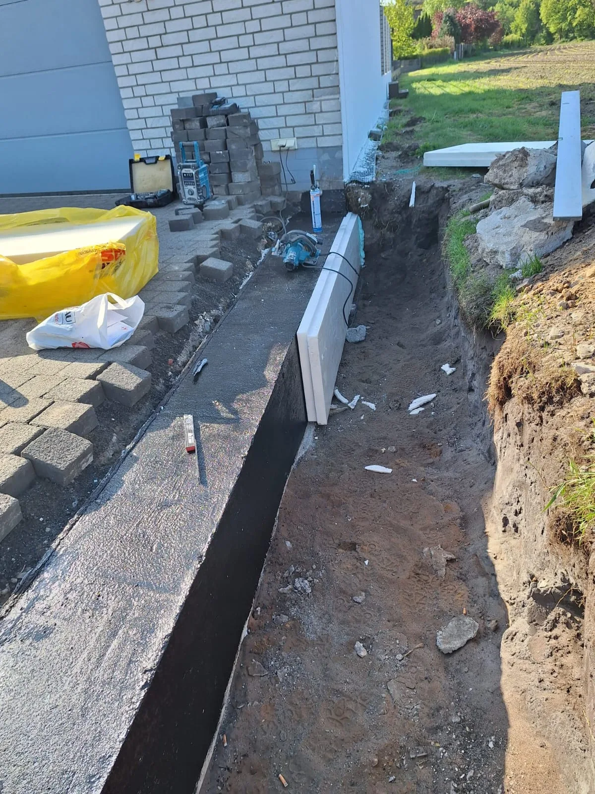 Baustelle mit Graben und abdichtendem Material für die Kellerabdichtung