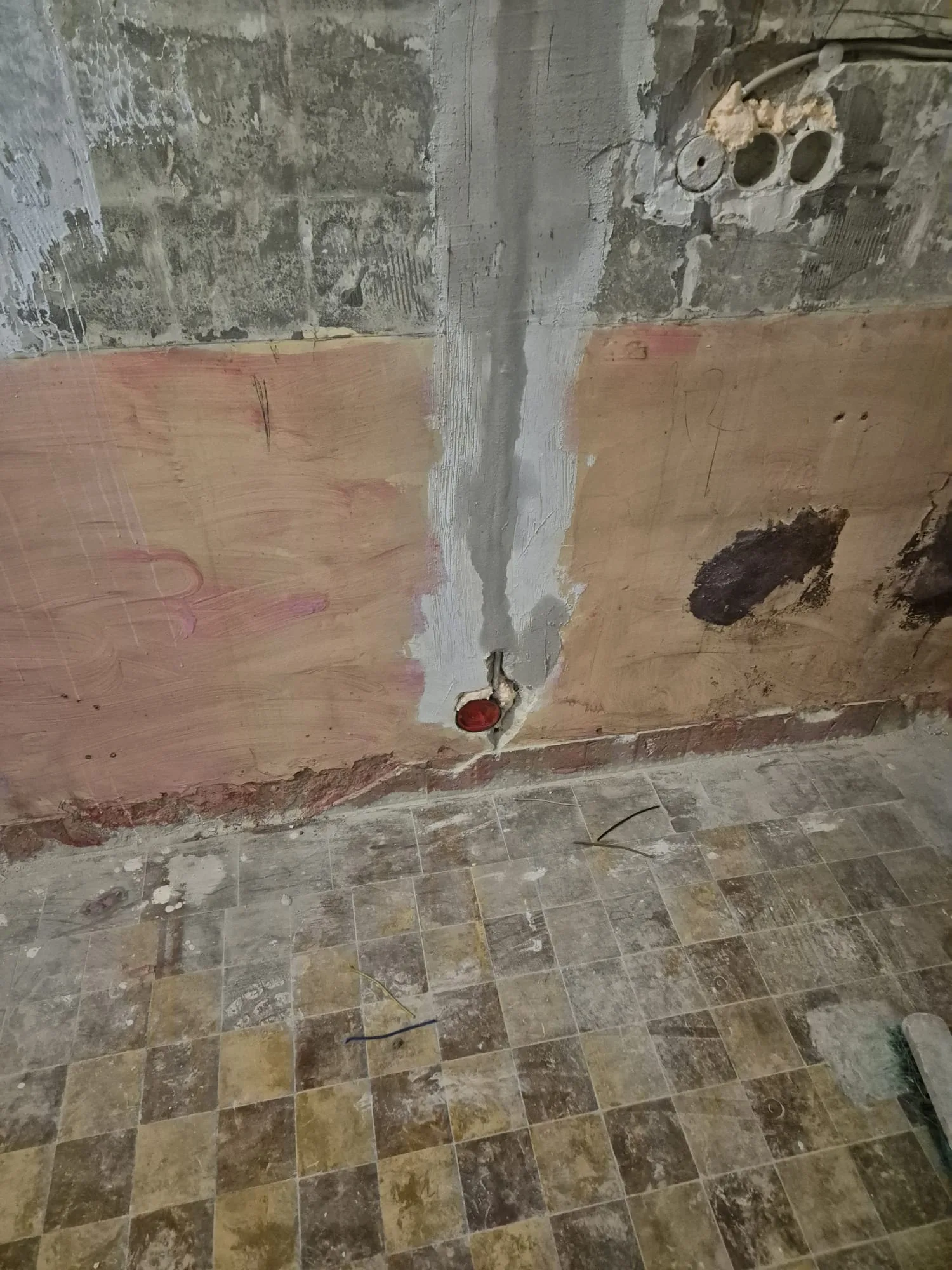 Sicht auf eine unvollendete Wand mit Putzschäden und Kabelinstallationen für Badsanierung