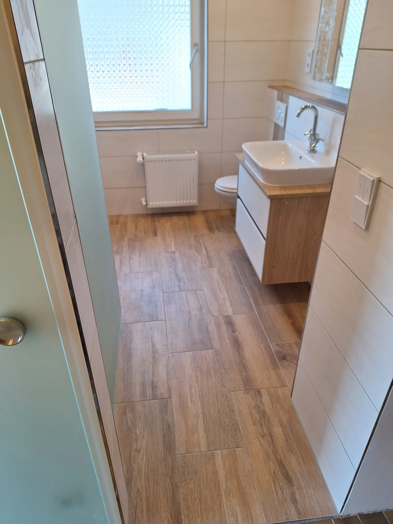 Modernes Badezimmer mit Holzoptik-Fliesen und eleganter Sanitäranlage