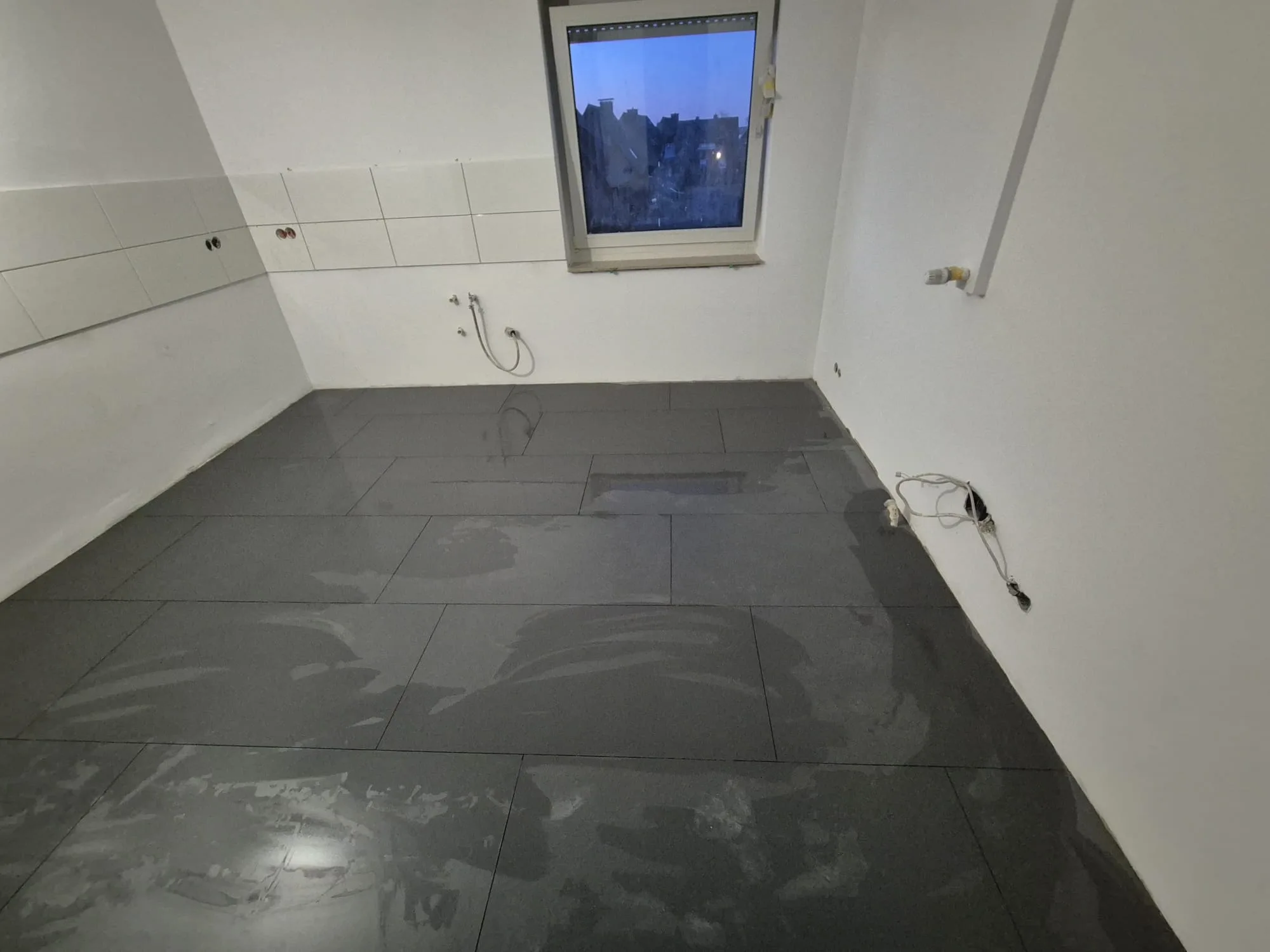 Verlegten Bodenfliesen in einem renovierten Raum mit hellem Fenster