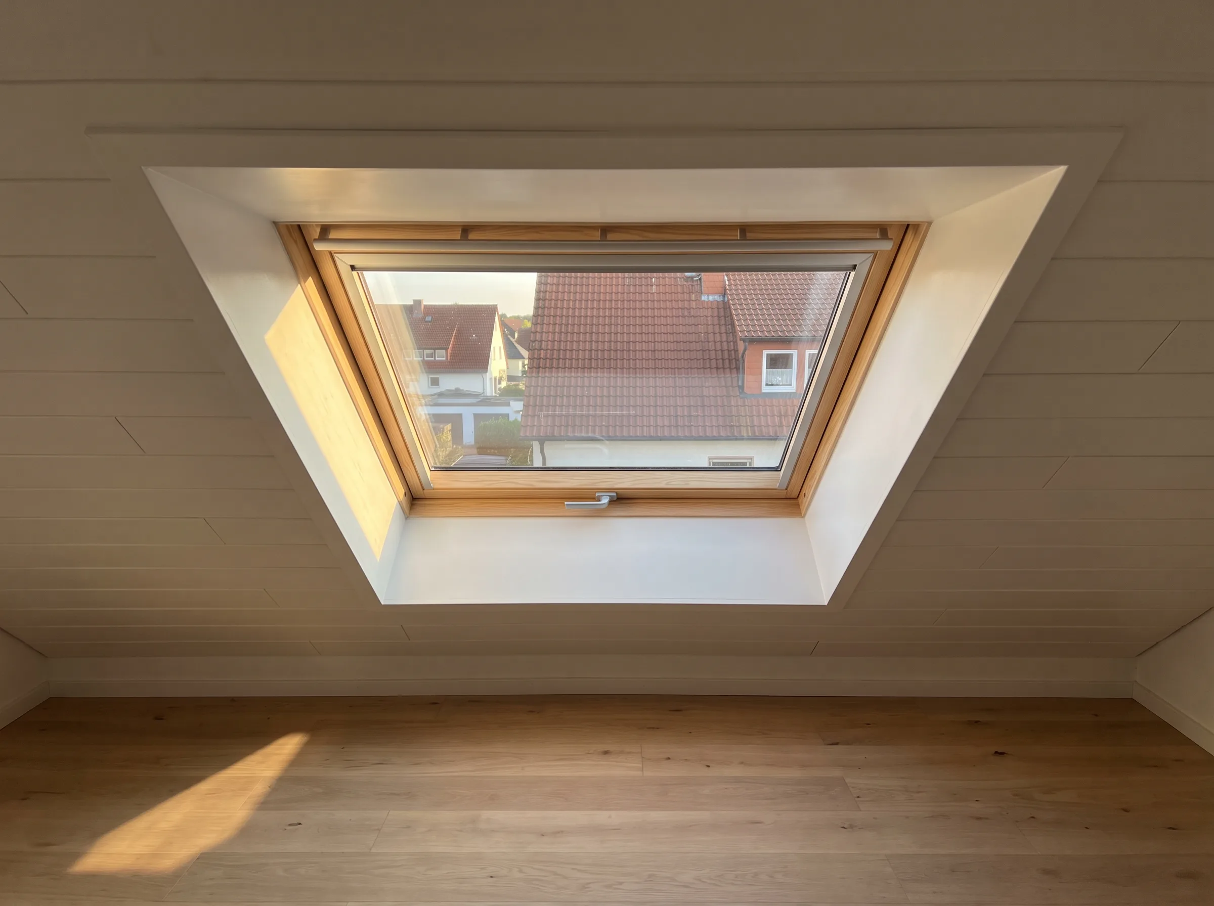 Dachfenster mit Holrahmen in einem hellen, modern gestalteten Dachraum