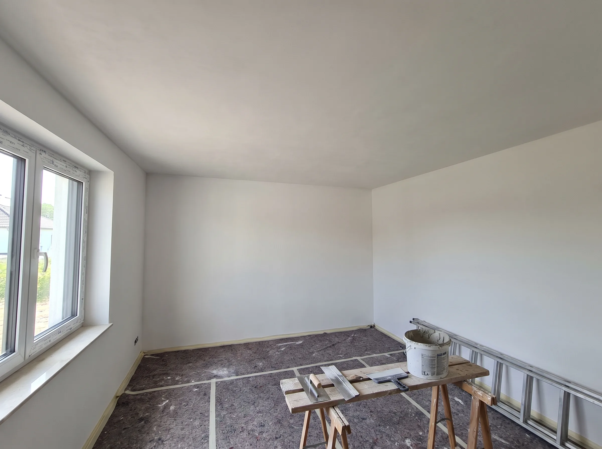 Renowierte Innenräume mit frischem Anstrich und vorbereiteten Wänden für weitere Arbeiten