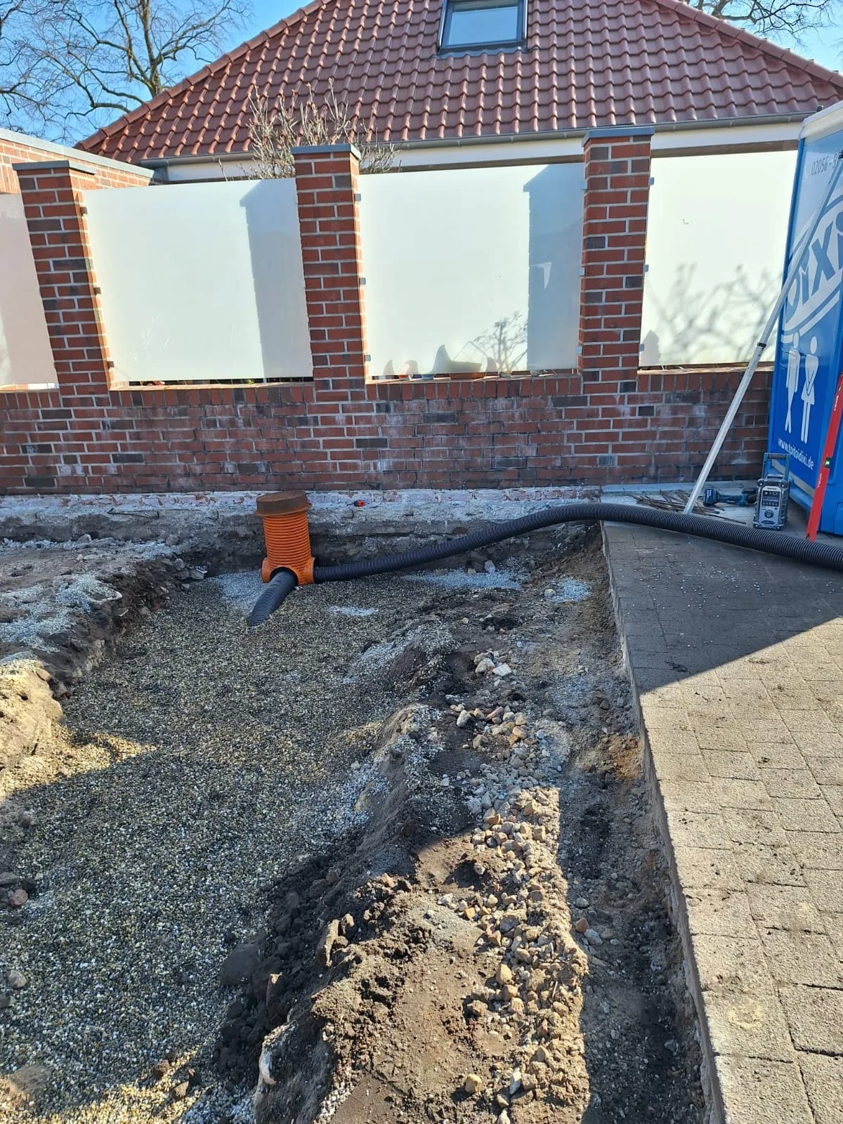 Baustelle mit Kiesbett und Rohr für Drainagearbeiten im Garten