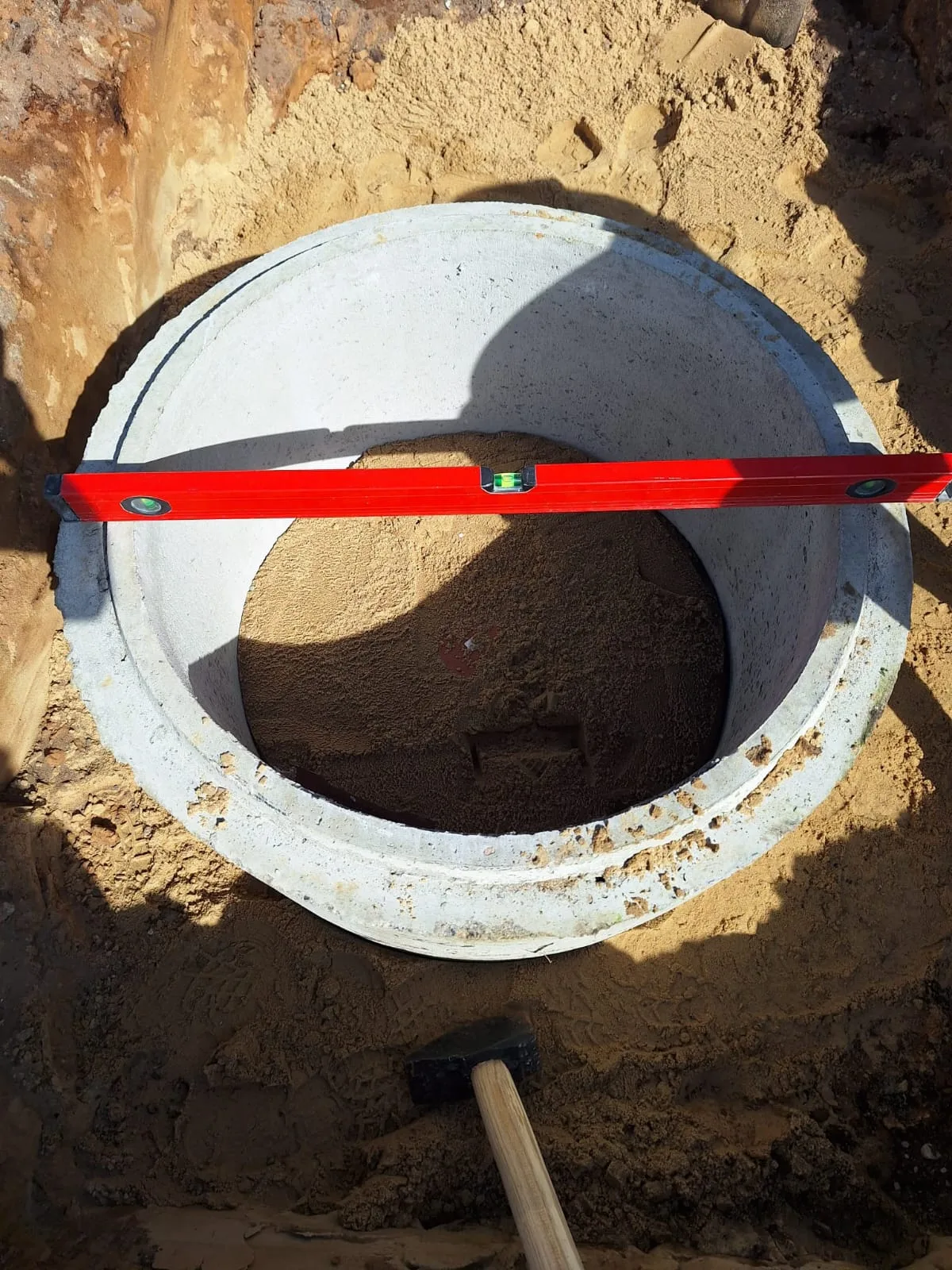 Sicht auf einen Betonkreis mit Wasserwaage, vorbereitet für Erdarbeiten oder Abwasserinstallation