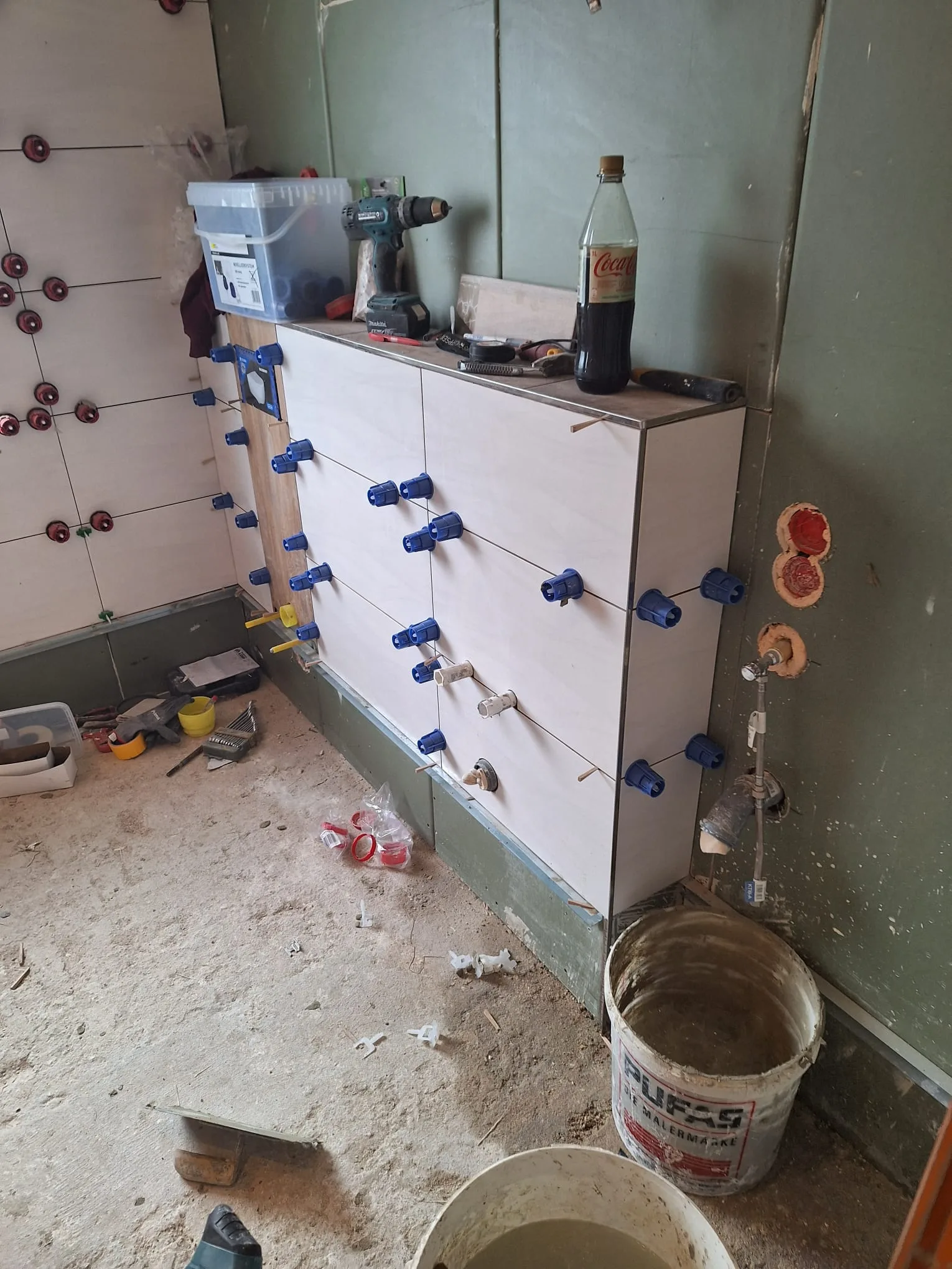 Fliesenverlegungsarbeiten in einem Badezimmer mit Werkzeugen und Materialien