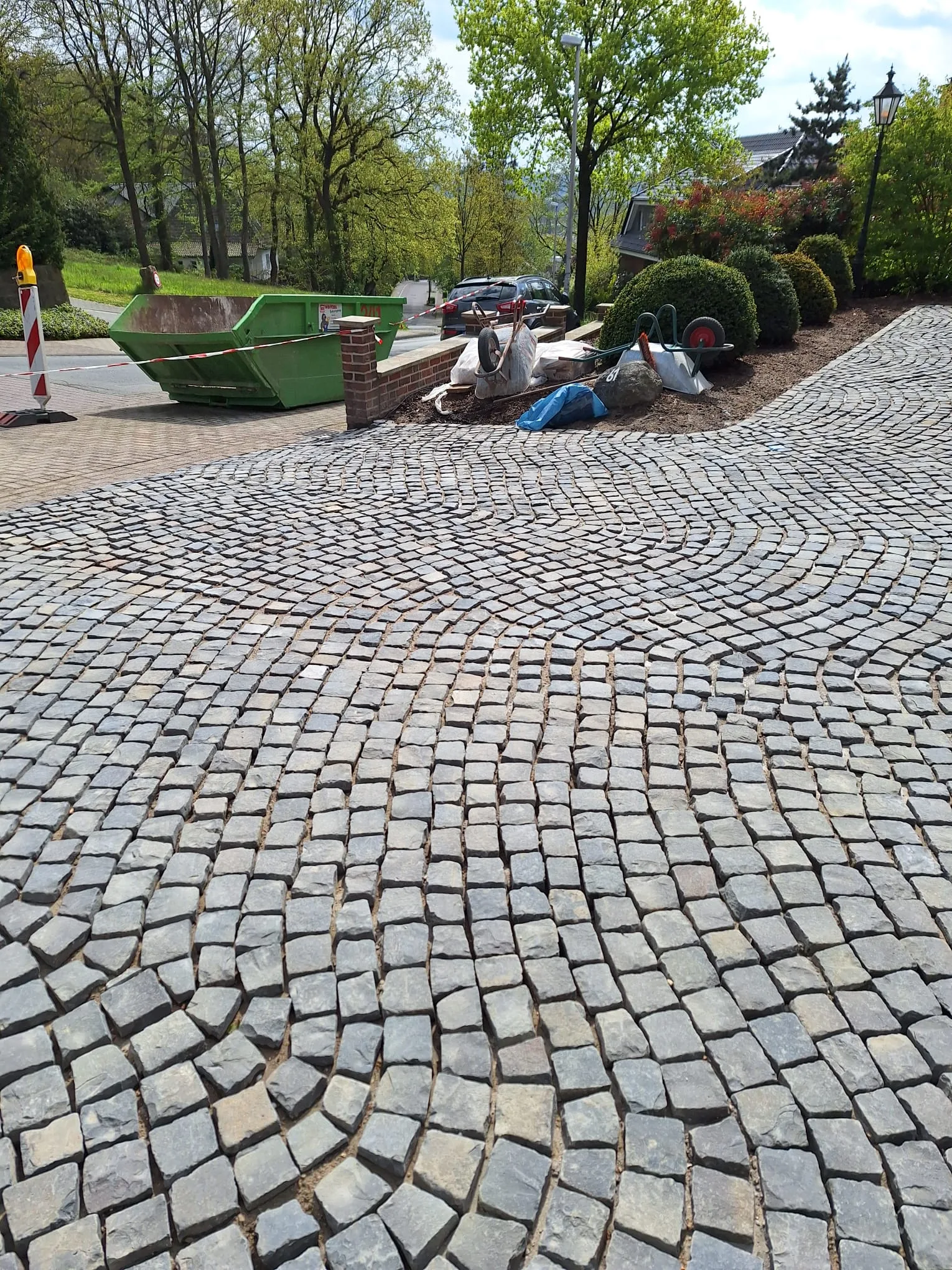 Pflasterarbeiten auf einer modernen Einfahrt mit Steinverlegung im Vordergrund