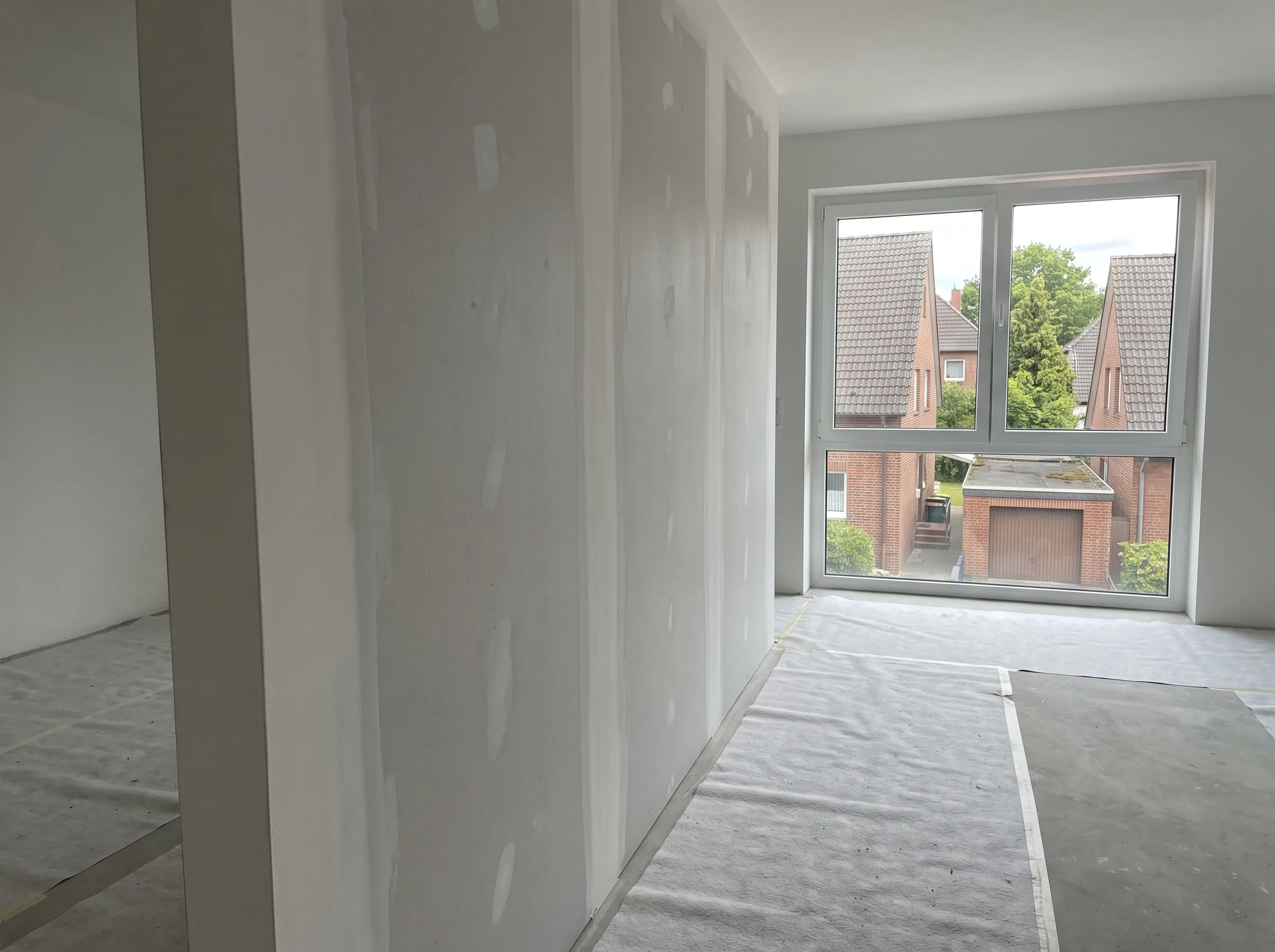 Innenraum mit Trockenbauwänden und großem Fenster, das Tageslicht hereinlässt