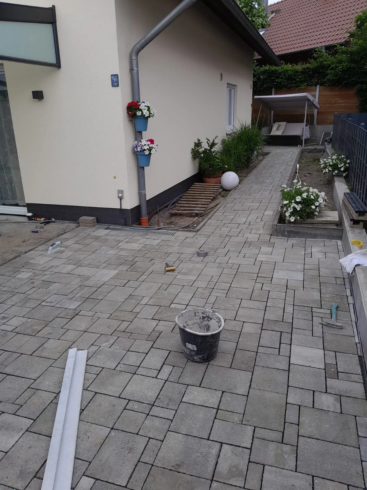 Pflasterarbeiten auf einem neuen Gehweg mit Bepflanzung und Bodenbelag