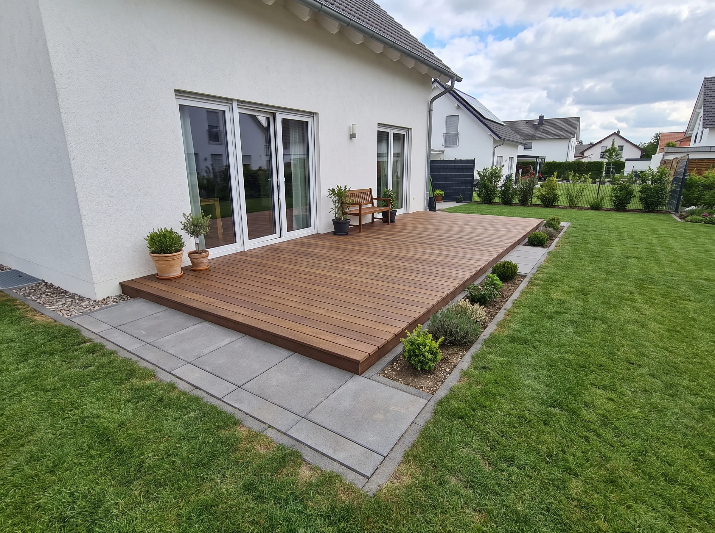 Holzboden-Terrasse mit Pflanzen und Rasen im Garten
