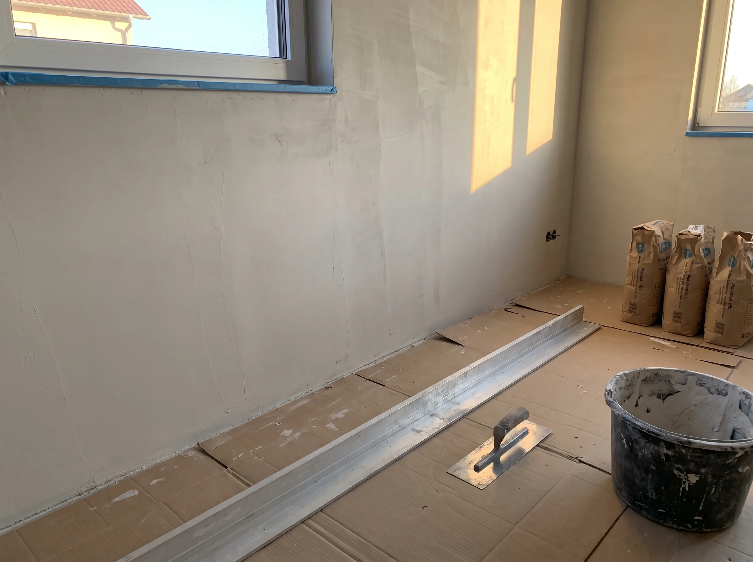 Innenansicht eines Raumes mit verputzten Wänden und Materialien für Malerarbeiten