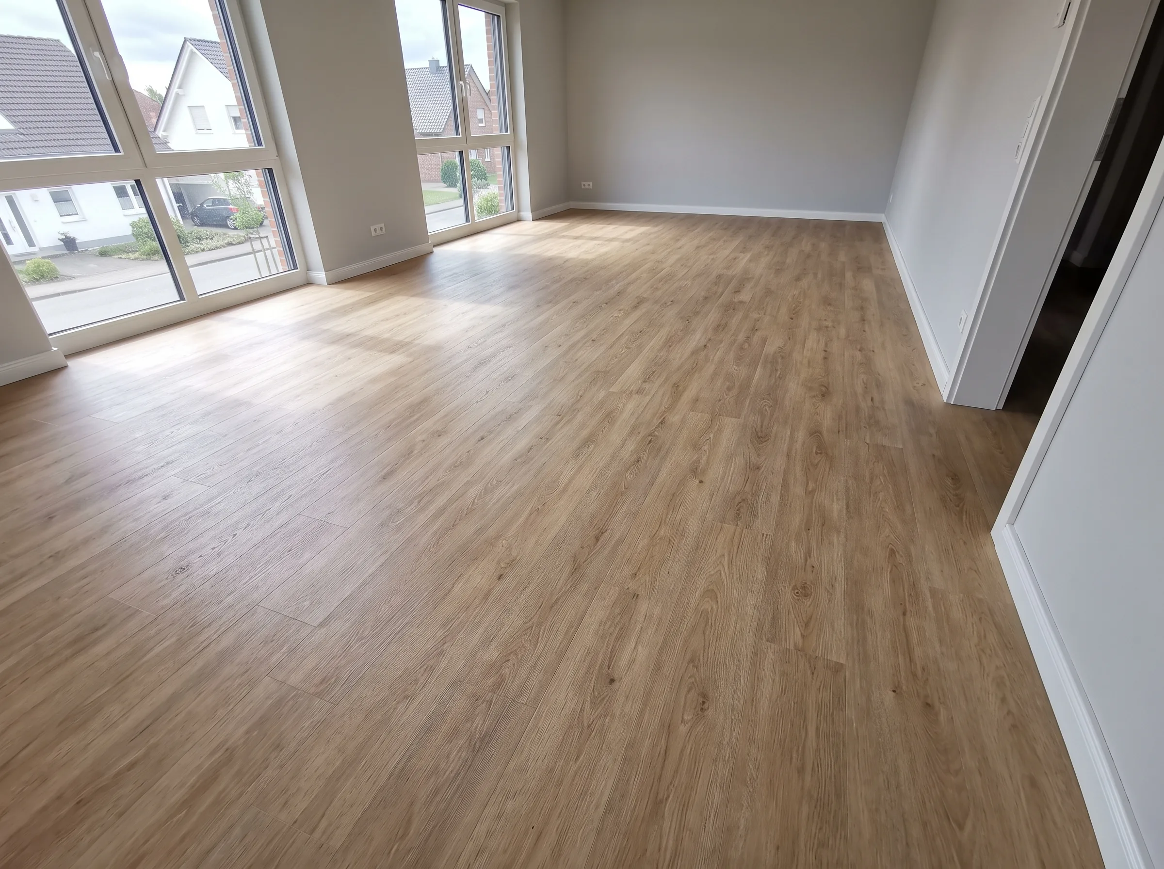 Neues Laminatboden in hellem Wohnraum mit großen Fenstern