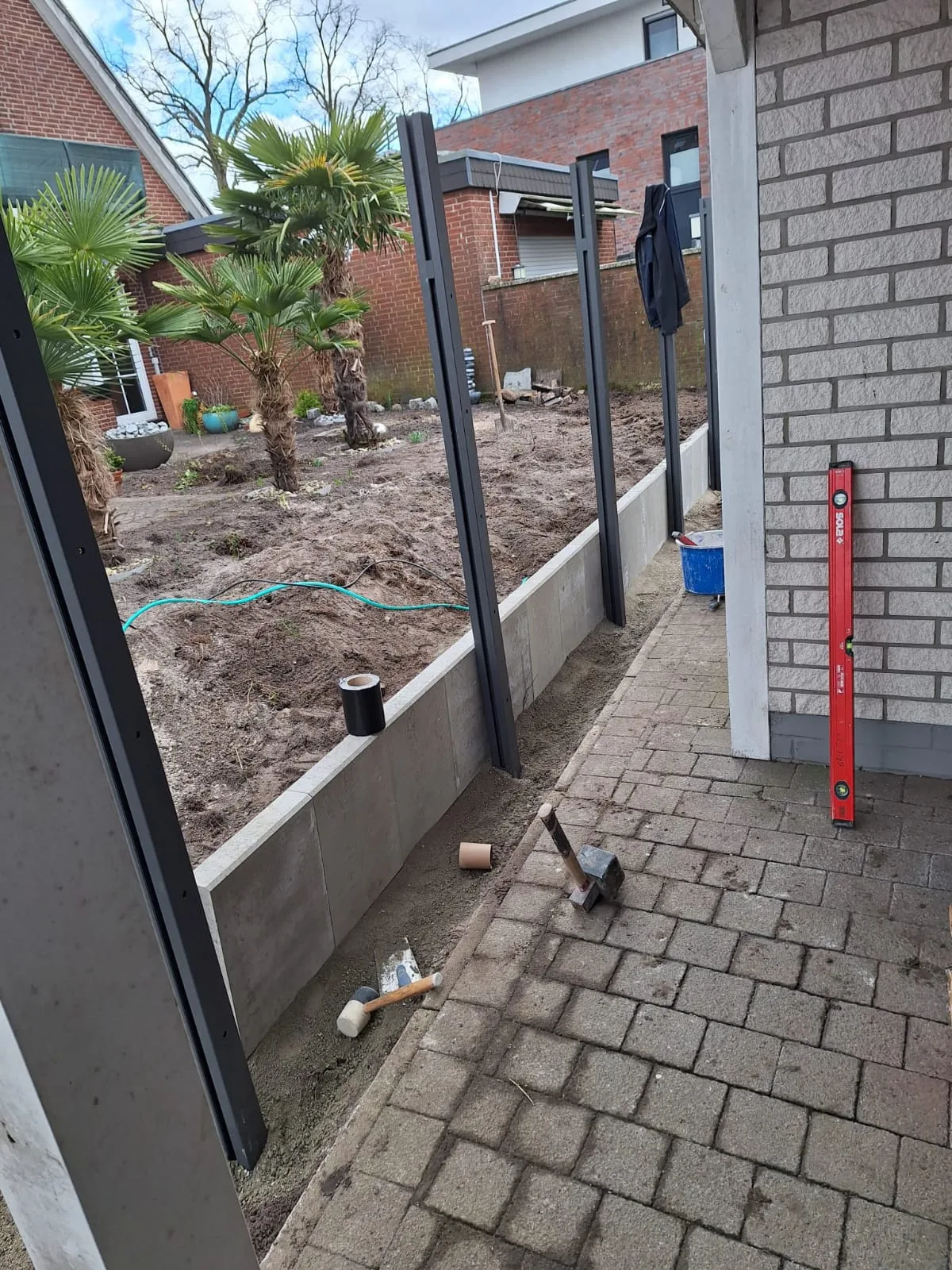 Sicht auf den Garten mit Steinkante und aufgestellten Zaunelementen