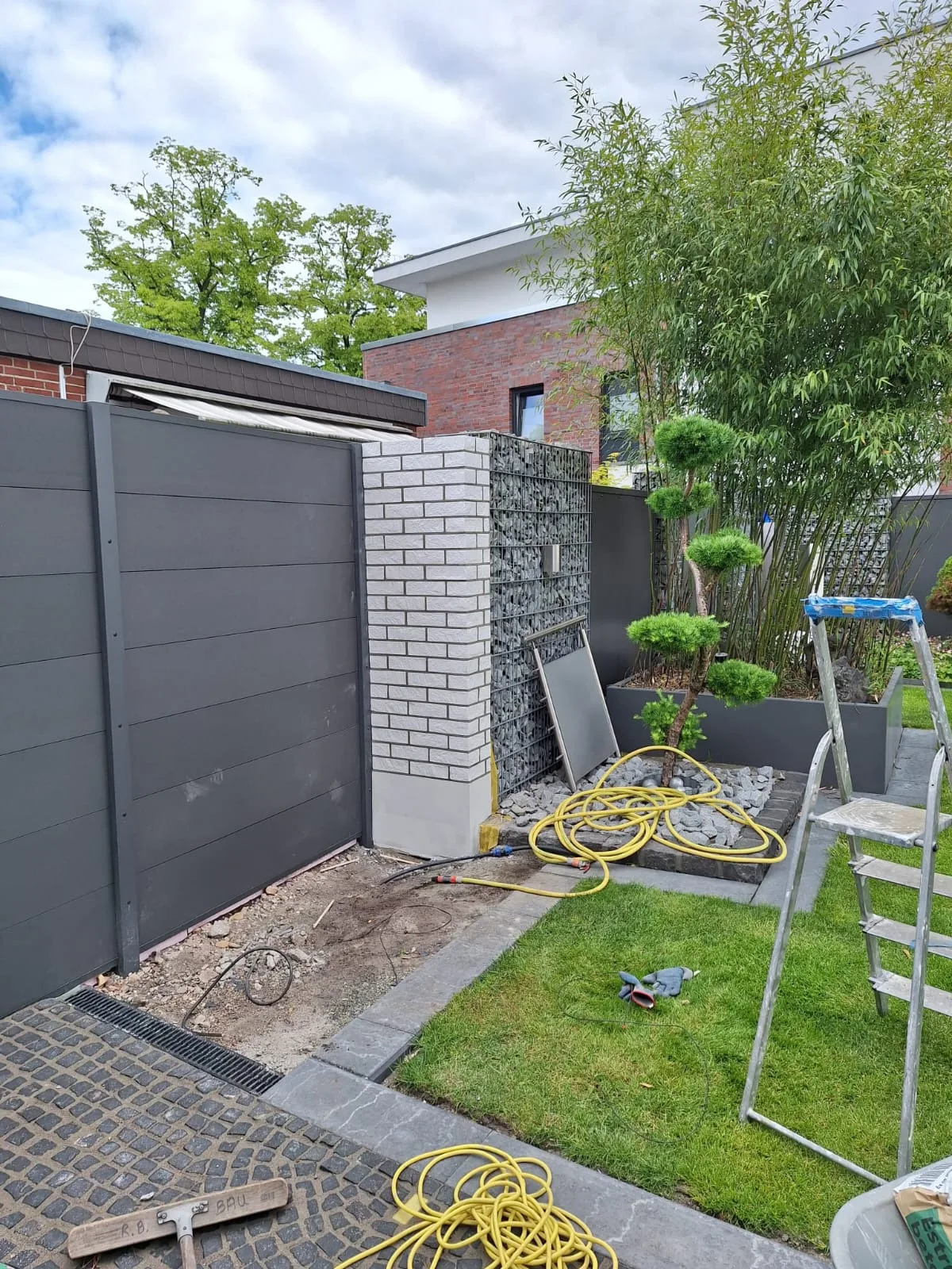 Gartenzaunbau mit modernen Materialien und einer abwechslungsreichen Bepflanzung im Hintergrund
